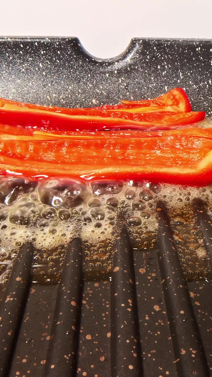 Melting butter sizzling on ridged grill pan in close cooking preparation view, vertical as a spread scrapes along edge