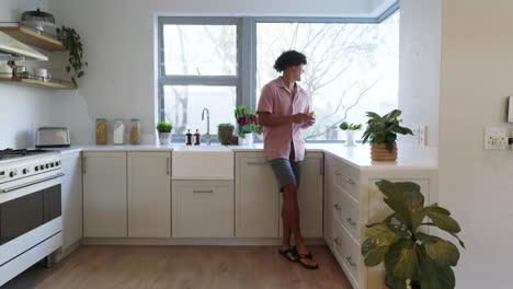 smiling man in kitchen leaning on counter, enjoying relaxed morning at home
