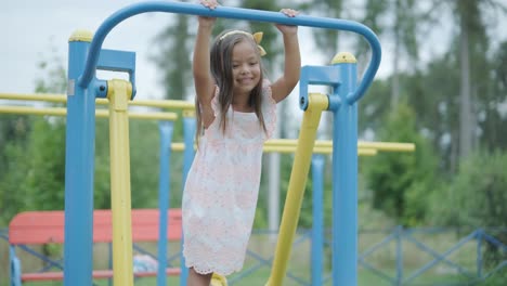 a pregnant mother and her young daughter enjoy playful time together at a playground in the park, surrounded by trees and greenery