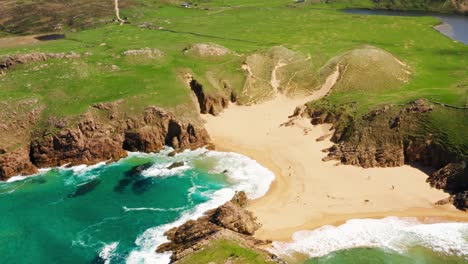 breathtaking aerial view of murder hole beach in ireland with clear water, cliffs, and visitors exploring the sandy shore