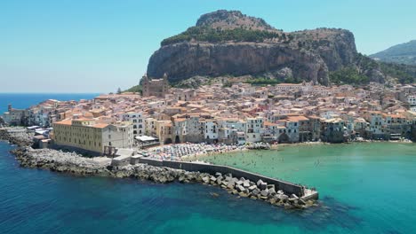 cefalu city, beach and rock during summer in sicily, italy - aerial 4k circling