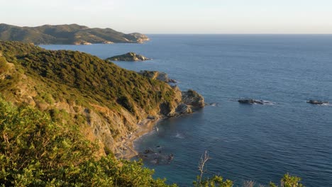 beautiful rocky coastline with vegetation in golden afternoon sun and blue water in chia, southern sardinia, italy