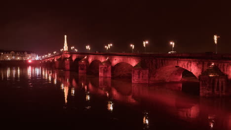fotografía nocturna del puente jacques-gabriel sobre el río loira iluminado con luces rojas en blois, francia.