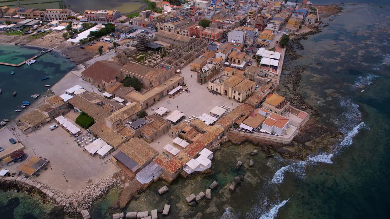 Drone view of Marzamemi, Italy. Charming Sicilian fishing town with boats, old stone houses, and sea