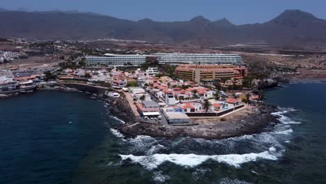 drone view of small village by the ocean with mountains in the background in la caleta, tenerife, canary islands, spain.