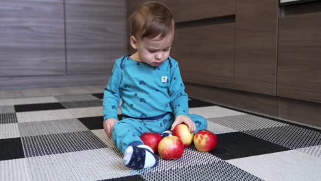 baby exploring apples in the kitchen