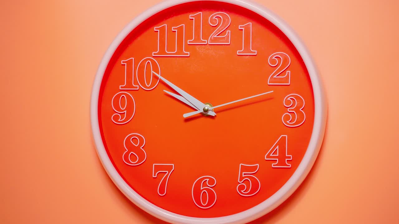 Close up time-lapse of modern wall clock approaching ten o' clock themes of deadline appointment late departure on an orange background.