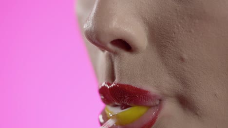 woman licking cherry popsicle with seduction, mouth close-up shot on pink background