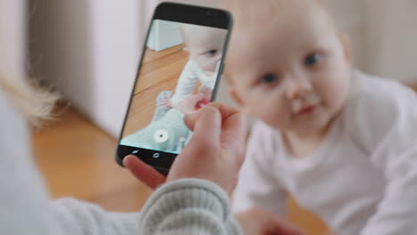 Madre-Tomando-Una-Foto-Del-Bebé-Usando-Un-Teléfono-Inteligente-Disfrutando-Fotografiando-A-Un-Lindo-Niño-Pequeño-Compartiendo-El-Estilo-De-Vida-De-La-Maternidad-En-Las-Redes-Sociales