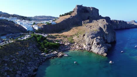 acropolis of lindos in rhodes, greece with houses and mediterranean sea during the day filmed with the drone