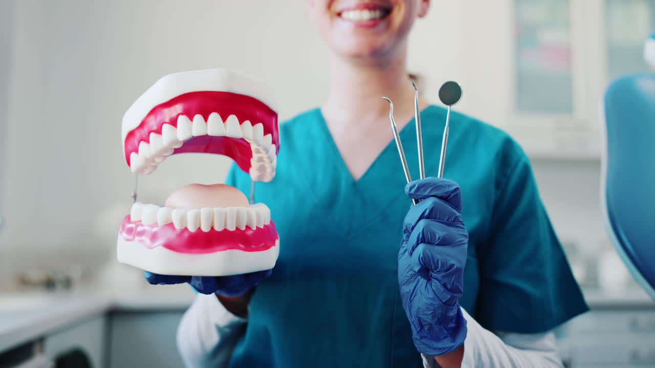 A dentist holding a denture and dental instruments