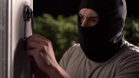a shadowy figure attempts to break into a house under the cover of night, showcasing tension and vulnerability in a suspenseful moment captured on film
