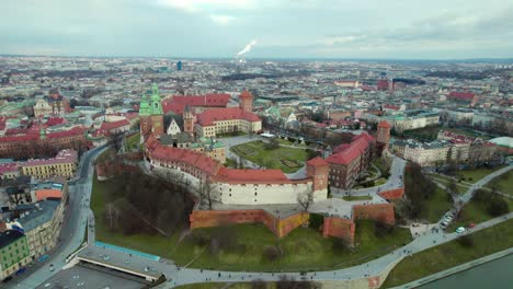 Cinematic-aerial-establishing-shot-flying-over-Krakow-Wawel-Royal-Castle-moving-forward,-city-center-fortress-with-the-old-town-and-Cracow-skyline