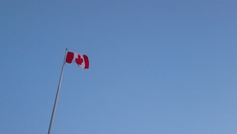 Vista-En-Cámara-Lenta-Paisaje-Zoom-Vista-En-La-Bandera-De-Canadá-Mientras-El-Viento-Sopla-En-El-Cielo-Del-Atardecer