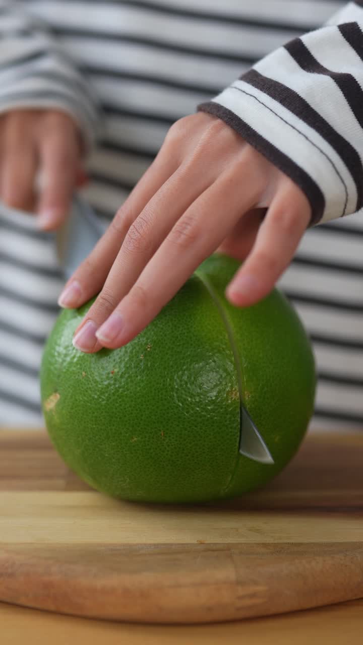 mujer cortando un pomelo verde