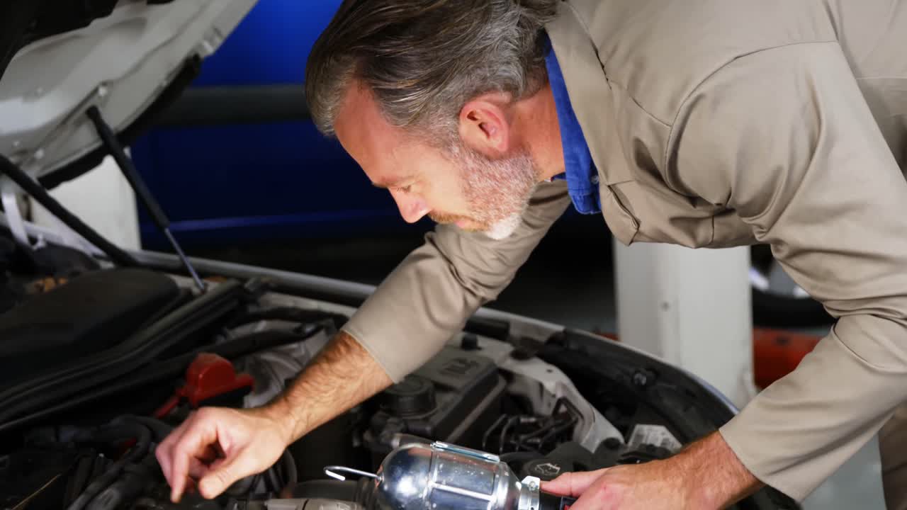 mecánico comprobando el aceite del motor del coche y mostrando los pulgares hacia arriba