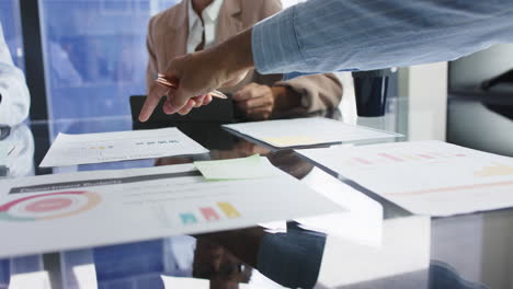 pointing at financial charts, business team discussing project in office meeting