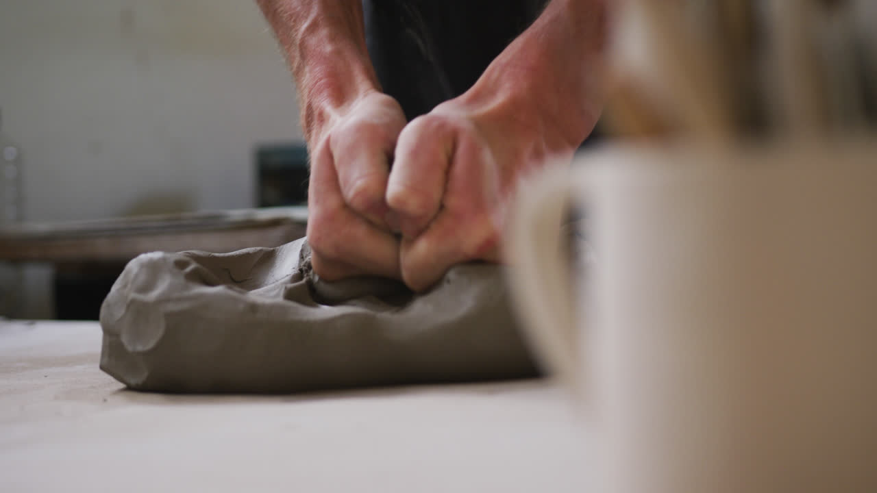 vista de cerca del alfarero masculino amassando la arcilla en el estudio de cerámica