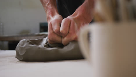 close up view of male potter kneading the clay at pottery studio