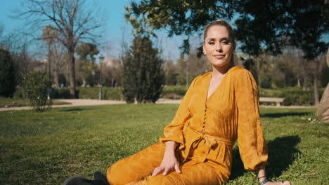 una joven elegante sentada en el césped al aire libre.