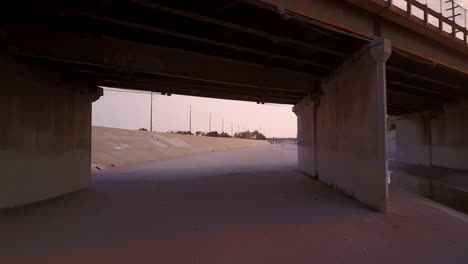 mosca de baixo ângulo sob a ponte no rio los angeles ao entardecer