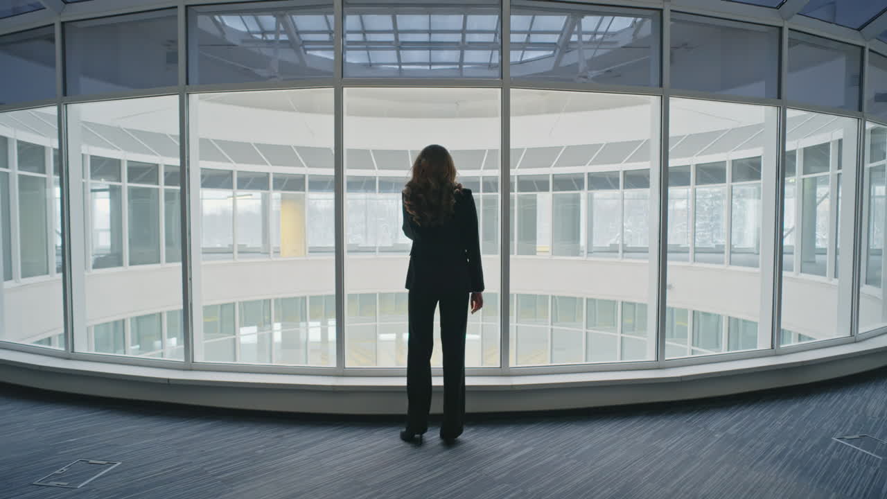 Manager calling mobile phone in lobby. Woman silhouette talk at office windows