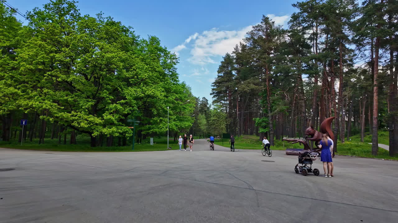 People enjoying a sunny day in a park with a large squirrel statue