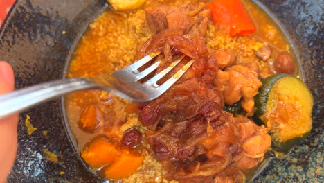 comiendo delicioso pollo tierno con cuscús y verduras en un restaurante, plato tradicional marroquí, carne cocida lentamente, tiro de 4k