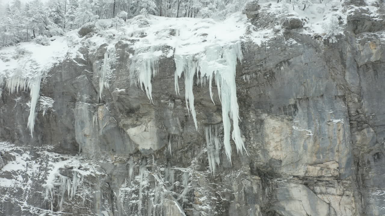 ángulo aéreo bajo de grandes hielos colgantes de la cresta de la montaña