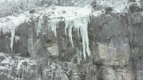 low angle aerial of large icicles hanging of mountain ridge