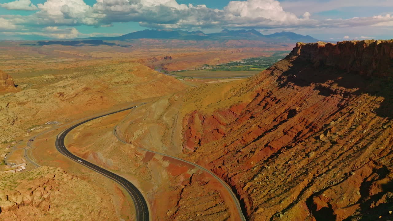 Rocky scenery of amazing canyons in Utah, USA. Motorway leading to the green valley. Stunning cloudscape at backdrop.