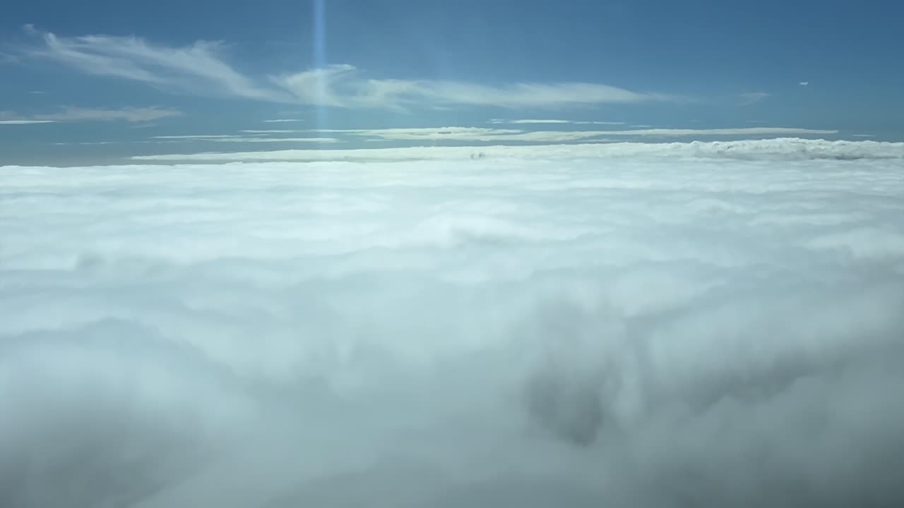 Immersive pilot POV FPV flying over a sea of clouds with the sun shining ahead. Aerial footage taken from a jet cockpit. Sunny day with a blue sky. 4K 60FPS