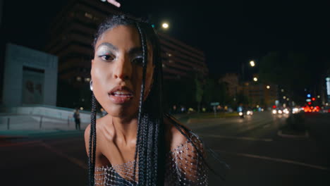 modelo de trenzas posando retrato de la ciudad nocturna. mujer de piel marrón mirando cámara