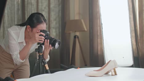 asian female photographer taking photos of women's shoes in home studio