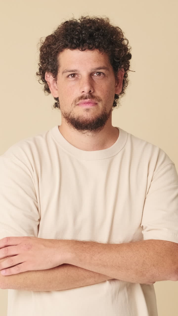 Young Man with Curly Hair Crossing Arms in Studio