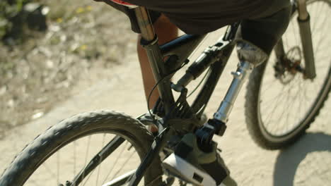 Close-up-shot-of-man-with-artificial-leg-pedaling-bike-in-nature