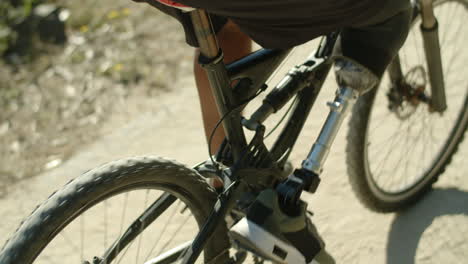 close-up shot of man with artificial leg pedaling bike in nature