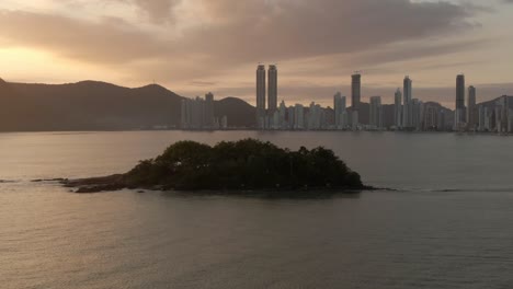 little island in the bay of a seaside city, sunset aerial