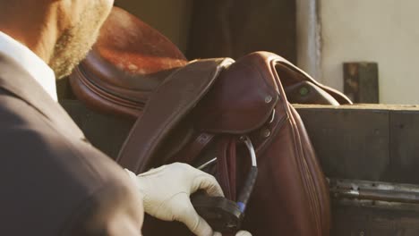 African American man preparing the saddle of the Dressage horse