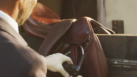 african american man preparing the saddle of the dressage horse