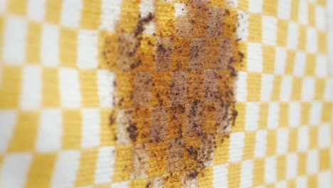 close-up of a dirty checkered fabric with a brown stain