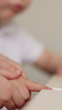 girl holds toddler boy hand and presses piano keys on blurry background closeup. elder sister teaches little brother to play melody on musical instrument