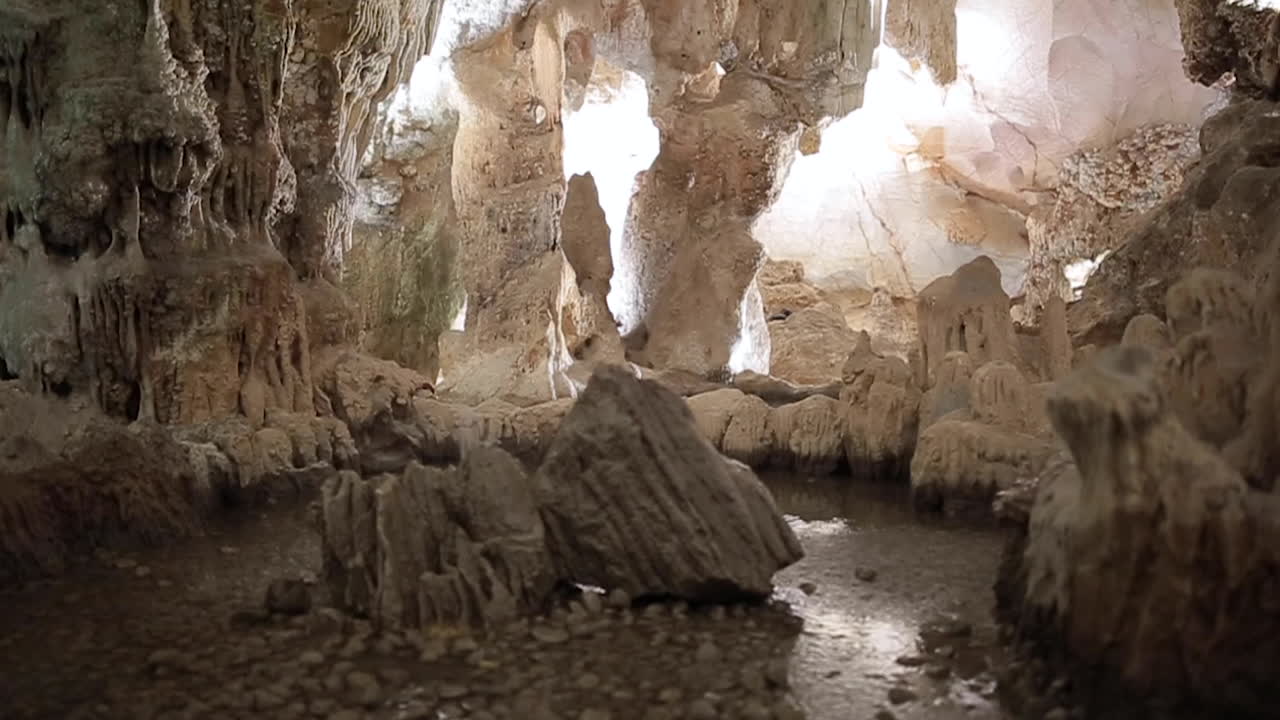 cueva de piedra caliza subterránea con estalactitas y estalagmitas blancas que recorren un túnel iluminado