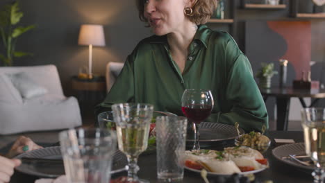 Portrait-Of-A-Pretty-Woman-Sitting-At-Dinner-Table,-Talking-And-Then-Smiling-At-Camera