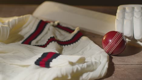 cricket still life with close up of bat ball gloves stumps jumper and bails lying on wooden surface in locker room 1