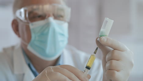 Close-up-shot-of-unrecognizable-nurse-or-doctor-in-gloves-filling-syringe-from-ampule-with-covid-19-vaccine.-Nurse-filling-injection-syringe-from-vial.-High-quality-4k-footage