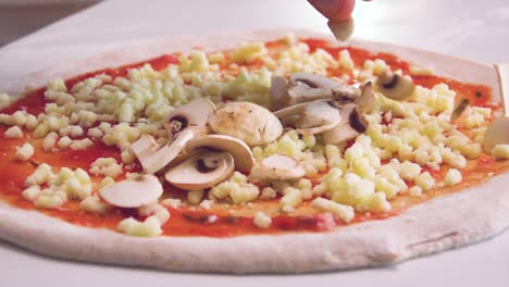 cook preparing pizza with mushrooms