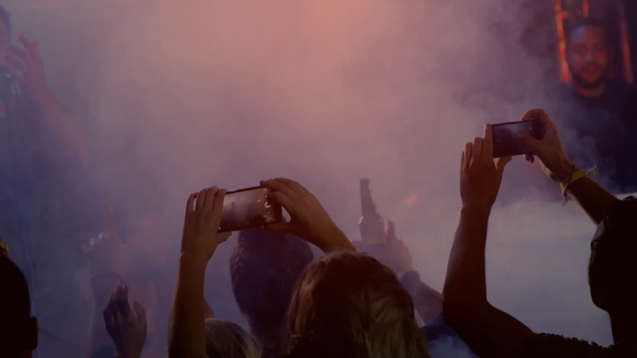 club audience raising smartphones through smoke in music marketing, displaying animated charts