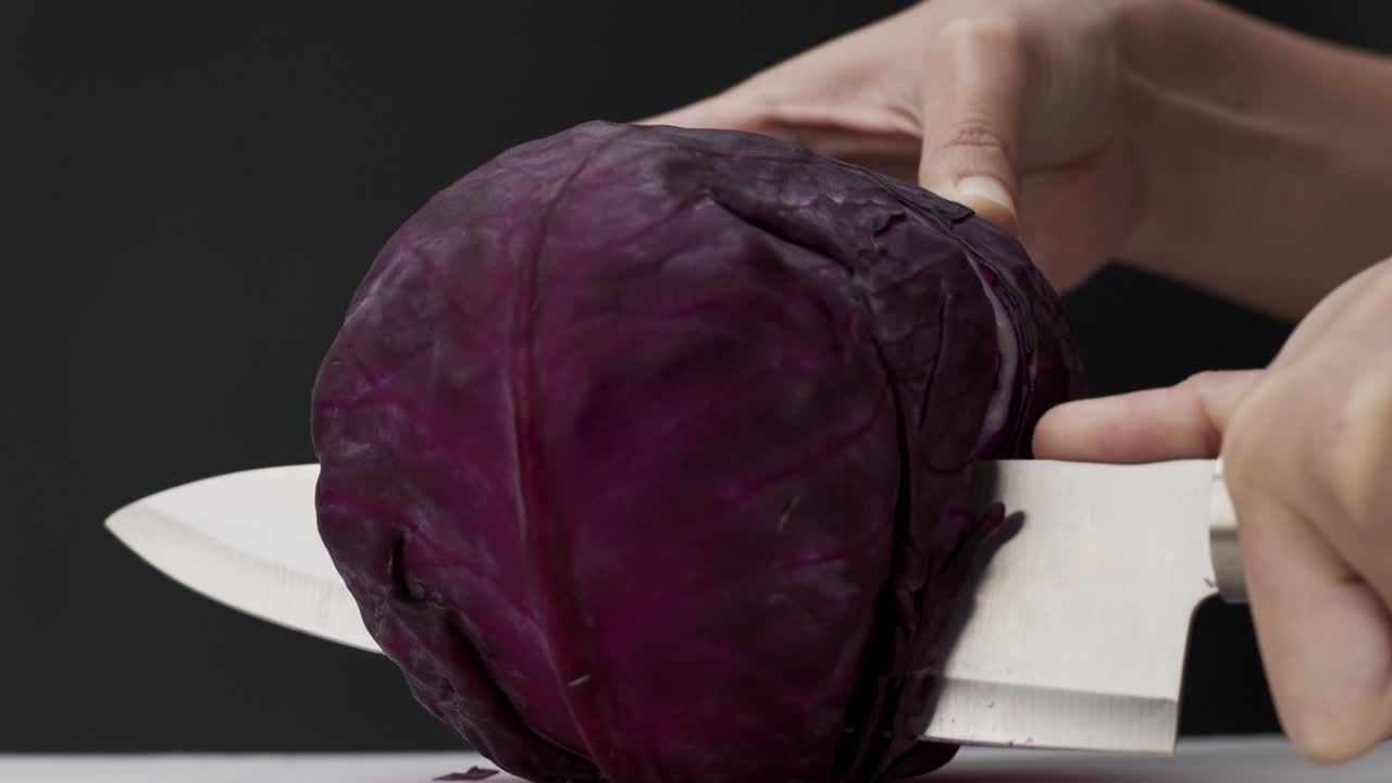 cortando el repollo púrpura por la mitad con un cuchillo.