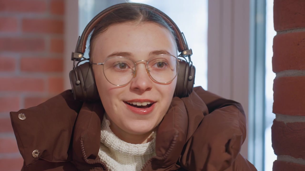 Young Woman in Headphones Warming Hands and Waving